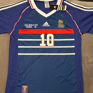 Zidane 1998 VM   - Nyskick/helt oanvänd Zinedine Zidane tröja från VM 1998. Tveka inte med att höra av er för mer information eller frågor!