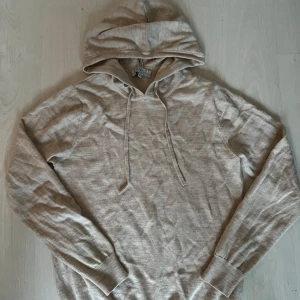 Beige hoodie från Ahlquist Clothing - Snygg beige hoodie från Ahlquist Clothing med huva och dragsnören. Tröjan är i mjukt material och har långa ärmar samt ribbade muddar. Perfekt för en chill och avslappnad stil.