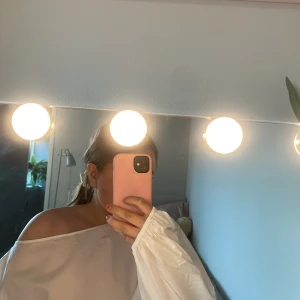 Vit oversized offshoulder skjorta från Nelly!’ - Säljer en vit oversized skjorta med offshoulder-design och långa, puffiga ärmar. Skjortan har en enkel och clean look med bred halsringning och är tillverkad i ett lätt bomullstyg. Perfekt för dig som gillar en avslappnad och trendig stil Den är helt ny och aldrig använd!!.