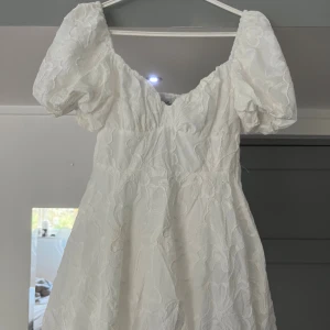 Vit kortklänning med puffärmar - Superfin vit kortklänning med puffiga ärmar och broderade detaljer. Supersöt och smickrande i passformen🥰prislappen sitter kvar och nypris är 419kr. Aldrig använd.