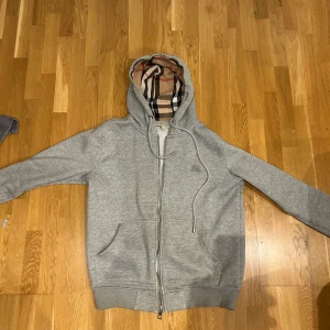 Burberry hoodie (läs beskrivningen) - Säljer min burberry eftersom dragkedjan är sönder och går därför inte stänga. Funkar ju att använda den med öppen dragkedja men går säkert att fixa ifall man är lite händig! Priset kan diskuteras vid snabb affär!