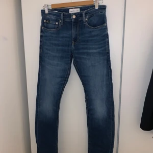 Blå skinny jeans från Calvin Klein - Snygga blå jeans från Calvin Klein med klassisk femficksdesign och diskret CK-logga på bakfickan. Jeansen har en smal passform och är tillverkade i stretchigt denim för extra komfort. Perfekta för dig som gillar en stilren och modern look. Vid minsta fundering hör av dig!😊 Mvh Victor 