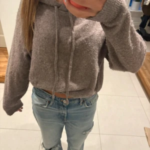 Beige hoodie i mjukt material - Supermysig beige hoodie med snörning i huvan och lång ärm. Tröjan är i ett fluffigt, stickat material och har en lite loose passform. Perfekt för chill dagar eller när du vill vara extra bekväm.