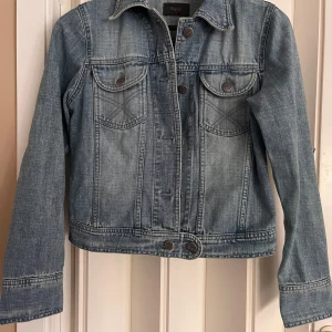 Klassisk jeansjacka från Filippa K - Snygg ljusblå jeansjacka från Filippa K med klassisk passform. Jackan har två bröstfickor med knappar, raka sömmar och stilrena detaljer. Perfekt för dig som vill ha en tidlös och cool look. Långärmad och i mjukt jeanstyg.