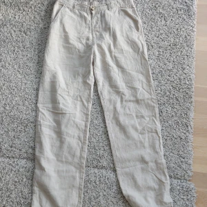 Beiga linnebyxor från Kappahl - Snygga och luftiga beiga linnebyxor från Kappahl i storlek 170. Byxorna har resår i midjan, raka ben och sidfickor. Sparsamt använda!