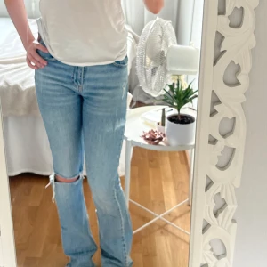 Ljusblå bootcut jeans med medelhög midja - Säljer ett par ljusblå bootcut jeans med slitning och hål på ena knät som tyvärr inte passar mig längre. De har en medelhög midja. Använda fåtal gånger. 