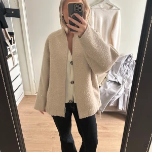 Beige teddyjacka från ONLY i storlek M - Säljer en beige teddyjacka från ONLY i storlek M. Jackan har en oversized passform, lång ärm och dragkedja framtill. Den är gjord i ett mjukt teddy-material som är perfekt för kyligare dagar. Enkel och stilren design som är lätt att matcha.