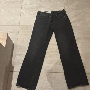 Svarta wide jeans från Zara - Säljer ett par svarta jeans från Zara i storlek 36. De är baggy och väldigt populära!Byxorna har en rak och bred passform med klassiska fem fickor och knappgylf. Materialet är jeans och färgen är svart med en något tvättad look. Perfekta för en avslappnad och trendig stil.