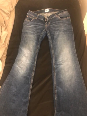 Blå bootcut jeans från 157, storlek L - Säljer ett par blå low waisted bootcut jeans från 157, modell Blaze. Jeansen har klassisk femficksdesign, snygga slitningar och kontrastsömmar. Jeansen är bara använda en gång och säljs eftersom de var lite för långa. 