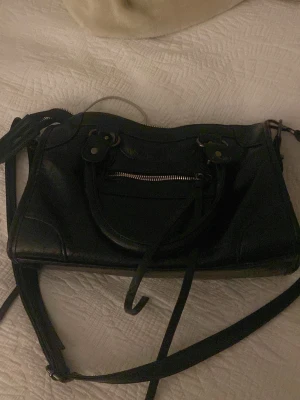 Svart väska, citybag inspererad  - Säljer en rymlig svart axelväska med både handtag och lång axelrem. Köpt sexond hand💞💞Bra skick, bara små slitage som ger en cool effekt. Väskan har metalldetaljer och rimlig insida. Skriv för frågor/pris kan diskuteras!💕💕 