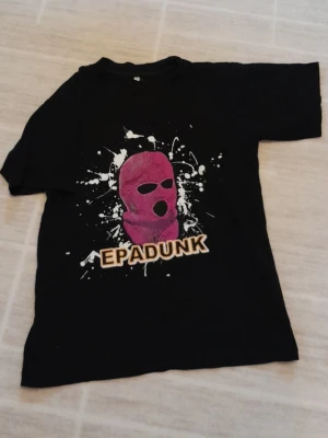 Svart EPADUNK t-shirt med fröken snusk - Svart t-shirt i 100% bomull med stort tryck av fröken snusk och texten EPADUNK på magen. T-shirten har korta ärmar och en klassisk passform. Perfekt för dig som gillar streetwear och vill sticka ut. !!endast swish +frakt!!