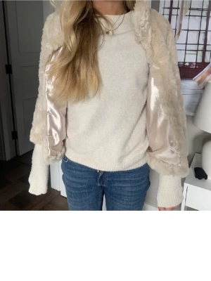 Tre kvart ärmad jacka - Säljer en supermjuk och fluffig beige teddyjacka med glansigt satin-foder på insidan. Jackan är kortare i modellen och har långärmade ärmar. Perfekt för dig som vill ha en mysig och trendig look under kyligare dagar.