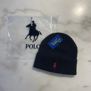 Polo Ralph Lauren stickad mössa med broderad logga - Klassisk mössa från Polo Ralph Lauren med den ikoniska broderade ryttaren framtill. Enkel och stilren modell som funkar perfekt till alla tillfällen. Mjuk och bekväm passform. I mycket bra skick.