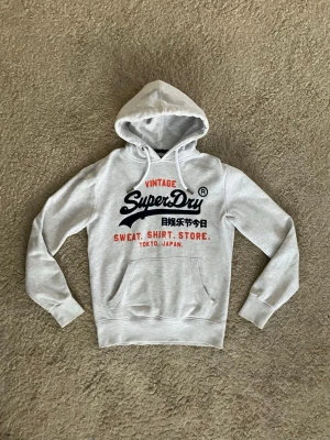 Superdry Hoodie - Grå Superdry Hoodie. - Tröjan är i princip nyskick då den används väldigt lite och sparsamt - Storlek: S - Pris: 549 kr - Först till Kvarn!
