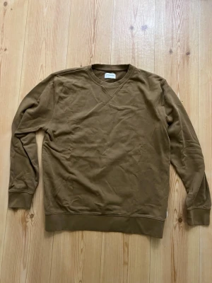 Brun sweatshirt från Lindbergh White - Säljer en enkel och stilren brun sweatshirt från Lindbergh White i storlek XL. Tröjan har rund halsringning, ribbade muddar och är tillverkad i mjuk bomull. Perfekt för dig som gillar en clean och avslappnad look.