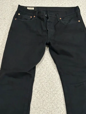 Svarta Levi's 501 Premium jeans W32 L32 - Svarta Levi's 501 Premium jeans med klassisk rak passform och knappgylf. Jeansen är tillverkade i robust denim och har fem fickor samt detaljer i kopparfärg. Perfekta för dig som gillar en tidlös och clean look.