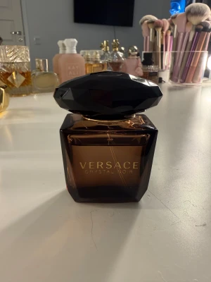 Versace Crystal Noir 30ml - Versace Crystal Noir Eau de Toilette, 30ml. Tillverkad i Italien. Snygg och lyxig flaska som sticker ut i samlingen. Perfekt storlek att ta med sig överallt. Knappt använt priset kan diskuteras 🩷