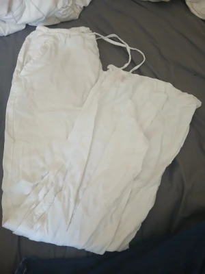 Vita linne byxor med snörning från 157 - Säljer ett par fräscha vita linne byxor från 157 i storlek XXS. De har elastisk midja med snörning och två sidofickor. Materialet känns mjukt och luftigt, perfekt för varma dagar. Enkel och clean design som funkar till många olika stilar.