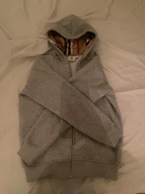 Grå hoodie från Burberry med dragkedja - Säljer en grå hoodie från Burberry i storlek m men skulle säga att passformen är small. Felfri från fläckar osv.
