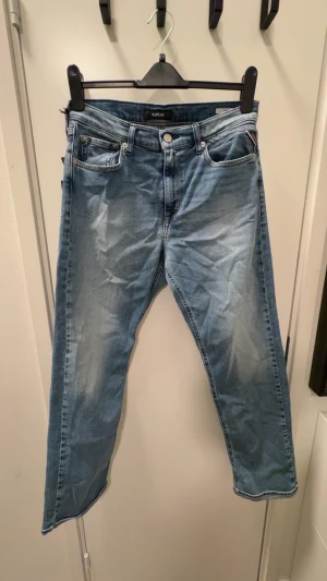 Replay ljusblå jeans THAD 16A - Säljer ett par snygga ljusblå jeans från Replay, modell THAD. Klassisk femficksdesign med raka ben och mörkblå broderi på bakfickorna. Jeansen har normal passform och är tillverkade i mjukt bomullsmaterial. Perfekt för dig som gillar stilrena och bekväma jeans. 10/10 skick men behövs styrkas vilket självklart görs innan leverans. 