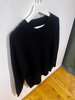 Svart stickad tröja Maison Margiela - Svart stickad tröja från Maison Margiela med klassisk rund hals och ribbade muddar. Tröjan har lång ärm och den ikoniska vita sömmen i nacken. Perfekt för dig som gillar minimalistisk och clean stil. Skick 11/10(oanvänd var för stor) tags me påse tillkommer. Mvh ItsForfits 🌟