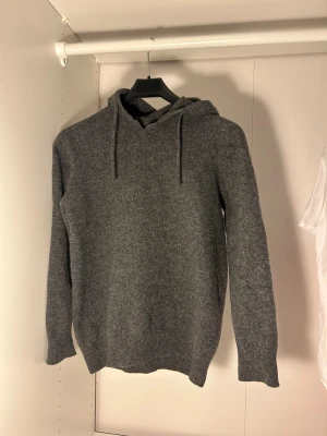 Grå Kashmir hoodie med huva  - Mysig grå hoodie i kashmir med huva och snörning. Perfekt för kyliga dagar och har en enkel, clean look som funkar till jeans eller mjukisbyxor. Storlek Smen passar även XS. Defekter finns 