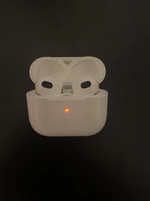 AirPods 3 - Apple AirPods 3 med laddningsetui. Fungerar och kan anslutas via Bluetooth. Synligt slitage smuts på  skalet, särskilt inuti locket. Perfekt för dig som vill ha trådlösa hörlurar till ett bra pris.