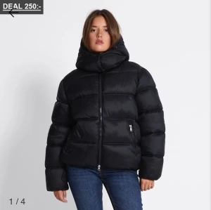 Svart pufferjacka Lager 157 - Säljer en svart pufferjacka från Lager 157 med stor huva och dragkedja framtill. Jackan har två sidofickor med dragkedja och justerbar dragsko nedtill. Perfekt för kalla dagar och riktigt skön att bära. Endast testad. Ny utan prislapp. 