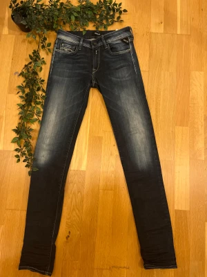 Mörkblå Replay Jeans - slim fit - Stilrena slim fit-jeans från Replay i en mörkblå, jämn tvätt. Bekvämt stretchmaterial som ger en snygg och följsam passform. Klassisk femficksdesign och dekorativa bakfickor med kontrastsömmar. Ett mångsidigt och tidlöst par jeans som passar alla tillfällen.