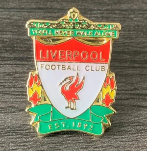 Liverpool FC pin i rött och grönt - Snygg pin med Liverpool Football Club-loggan, detaljerad med rött, grönt, vitt och guld. Texten 'You'll Never Walk Alone' och 'EST. 1892' syns tydligt. Perfekt för att visa ditt stöd för klubben på jackan eller väskan.