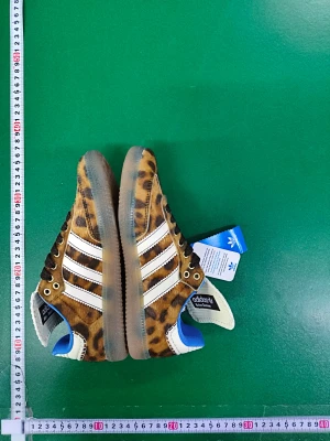 Adidas Samba leopardmönstrade sneakers - Unika Adidas Samba sneakers med leopardmönster i brunt och beige, vita detaljer och blå insida. Skorna har klassiska tre ränder på sidan, snörning och platt gummisula. Ovandelen är i pälsliknande syntetmaterial och tungan är vit med Adidas-logga.