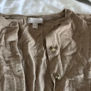 Beige/brun kofta från H&M, storlek S - Säljer en beige kofta från H&M i storlek S. Koftan har långa ärmar, rund halsringning och knäppning framtill med små knappar. Materialet känns mjukt och lätt, den är brun/beige💕