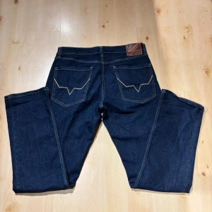 Pepe Jeans W34, L33 - Snygga mörkblå jeans från Pepe Jeans med klassisk rak passform och kontrastsömmar. Jeansen har fem fickor, coola bakfickor med unik söm och läderpatch med logga bak i midjan. Perfekta för dig som gillar stilrena och tidlösa jeans.