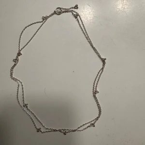 Silverhalsband med hjärtan från Drakenberg - Snyggt och stilrent halsband i silver från Drakenberg. Kedjan är tunn och dekorerad med små hjärtan längs hela halsbandet, vilket ger en söt och romantisk vibe. Perfekt för dig som gillar diskreta men ändå unika smycken.