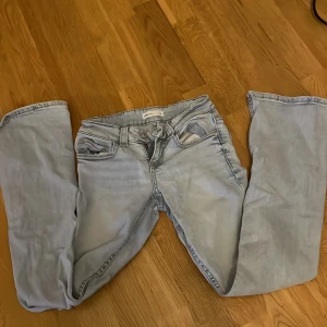 Ljusblå jeans från Gina Tricot, strl 34 - Säljer ett par ljusblå jeans från Gina Tricot, modell Perfect Jeans. De har klassisk femficksdesign med snygga ficklock och knappdetalj bak. Low waist bootcut jeans.