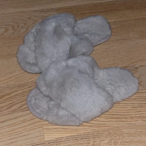 Grå fluffiga tofflor - Supermysiga grå tofflor med fluffig pälsimitation. Storlek 37/38. Skön sula.