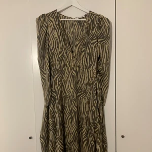 Zebramönstrad långklänning med v-ringning - Zebramönstrad Klänning från Adoore i stl 36, går att knyta i midjan.