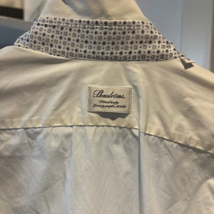 Vit Stenströms skjorta  - Vit skjorta från Stenströms med fitted body-passform. Kragen har ljusblåa mönster på insidan och är hel vit på utsidan. Skjortan är tillverkad i lyxig bomullspoplin och har långa ärmar. Perfekt för dig som gillar stilrena och lyxiga detaljer. Nypris 1599kr! Innan skjortan skickas kan den strykas om de vill de! Passar dig som är mer eller mindre runt 170cm pris kan diskuteras vid snabbaffär 