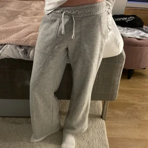 Grå mjukisbyxor från 157 - Grå mjukisbyxor från lager 157 med bred resår och snörning i midjan. Storlek 140 men passar i 150 också. Byxorna har stora fickor fram och bak samt är tillverkade i mjukt bomullsmaterial. Perfekta för chill dagar eller när du vill vara extra bekväm.