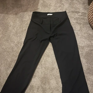 Svarta kostymbyxor från Nelly i storlek 32  - Snygga svarta kostymbyxor från Nelly  med låg midja och raka ben. Byxorna har en klassisk look och är gjorda i ett  material som sitter skönt. Perfekta för dig som gillar stilrena outfits 