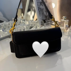 Svart axelväska  i skinn - Snygg svart axelväska med guldfärgade metalldetaljer. Väskan har ett klassiskt, stilrent utseende med lock, magnetlås och innerfack med dragkedja. Perfekt storlek för det viktigaste och en riktigt tidlös accessoar.