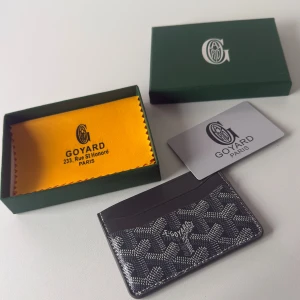 Svart och grå G yard korthållare i skinn - Exklusiv korthållare från G yard svart skinn med ikoniskt mönster och vita detaljer. Slimmad design med flera kortfack, perfekt för dig som vill ha stilren och lyxig accessoar. Levereras med original ask och tygpåse.