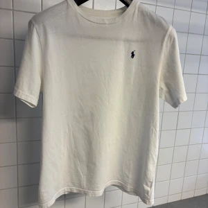 Vit t-shirt från Polo Ralph Lauren XL (170) - Vit t-shirt från Polo Ralph Lauren i bomull med klassisk passform och korta ärmar. Diskret broderad logga på bröstet. Enkel och stilren design som funkar till allt.