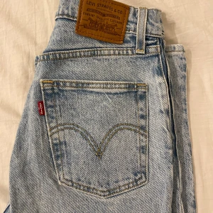 Levi's Ribcage Straight ljusblå jeans - Säljer ett par Levi's Ribcage Straight jeans i ljusblå tvätt. De är högmidjade med raka ben och klassiska fem fickor. Jeansen är i premiumkvalitet med snygga detaljer som kopparfärgade nitar och Levi's patch bak. Perfekta för en chill och trendig look.