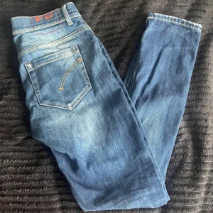DonDup George - Snygga blå skinny jeans från DonDup med klassisk femficksdesign och kontrastsömmar. Jeansen har en smal passform och är tillverkade i stretchigt denim för extra komfort. Perfekta för dig som gillar en tajtare look och vill ha ett par stilrena jeans i garderoben.