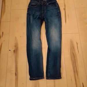 Blå jeans från Jack & Jones - Snygga blå jeans från Jack & Jones med klassisk femficksdesign och kontrastsömmar. Jeansen har en något smalare passform och är tillverkade i slitstarkt denimtyg. Perfekta för dig som gillar en tidlös och stilren look.