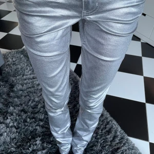silver jeans - Säljer ett par glansiga silverfärgade jeans från Esmara i skinny fit. Byxorna har klassisk femficksdesign, normal midja och smal passform hela vägen ner. Aldrig använd eller tvättad. Helt perfekt för fester och halloween.
