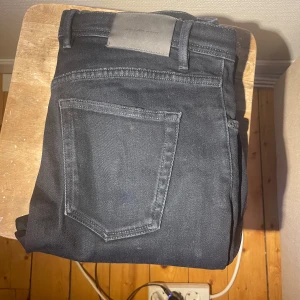 Svarta jeansbyxor från Massimo Dutti - Snygga svarta jeansbyxor från Massimo Dutti med klassisk femficksdesign och diskret logopatch baktill i midjan. Jeansen har en rak passform och är tillverkade i mjukt bomullsmaterial som ger en skön känsla hela dagen.