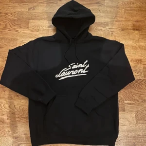 Saint Laurent hoodie - Riktigt fet och eftertraktad hoodie med saint laurent loggan. Storlek M, skick 10/10!! Är lite osäker på äktheten så därför är priset just nu på 1149kr! Nypris runt 7000! Ser precis ut som originalet! Tveka inte med att ställa frågor!