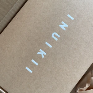 Beige/vita sandaler från Inuikii, strl 40 - Säljer ett par snygga sandaler från Inuikii i beige med flätad ovandel och vit platt sula. Sandalerna har en modern design och är perfekta för dig som gillar trendiga och bekväma skor. Helt oanvända och nya!